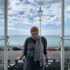 Student looking at the camera smiling with a seaside background