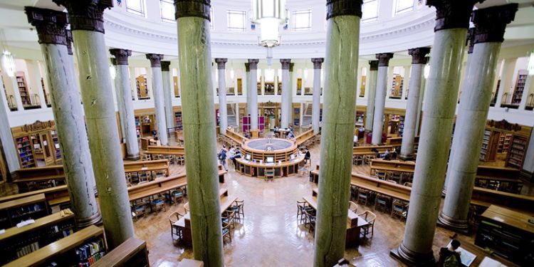 Library with pillars, desks and shelves.