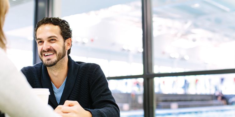 Student smiling across a desk facing another person.