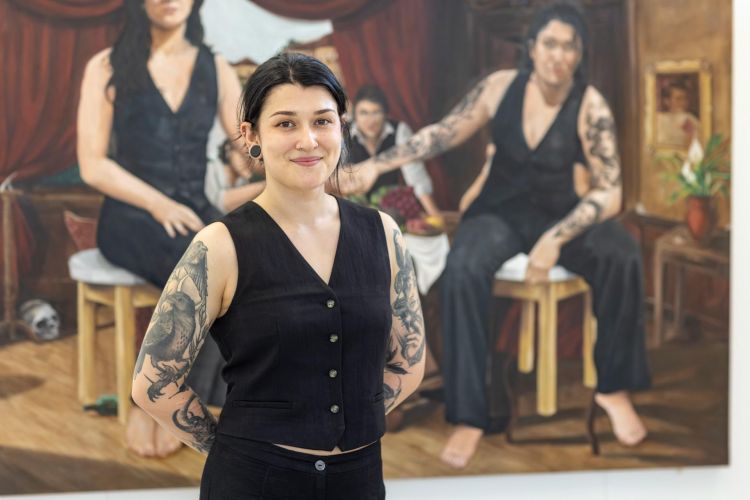 Artist Rhiannon Piper standing in front of oil painting titled The Artist by Rhiannon Piper