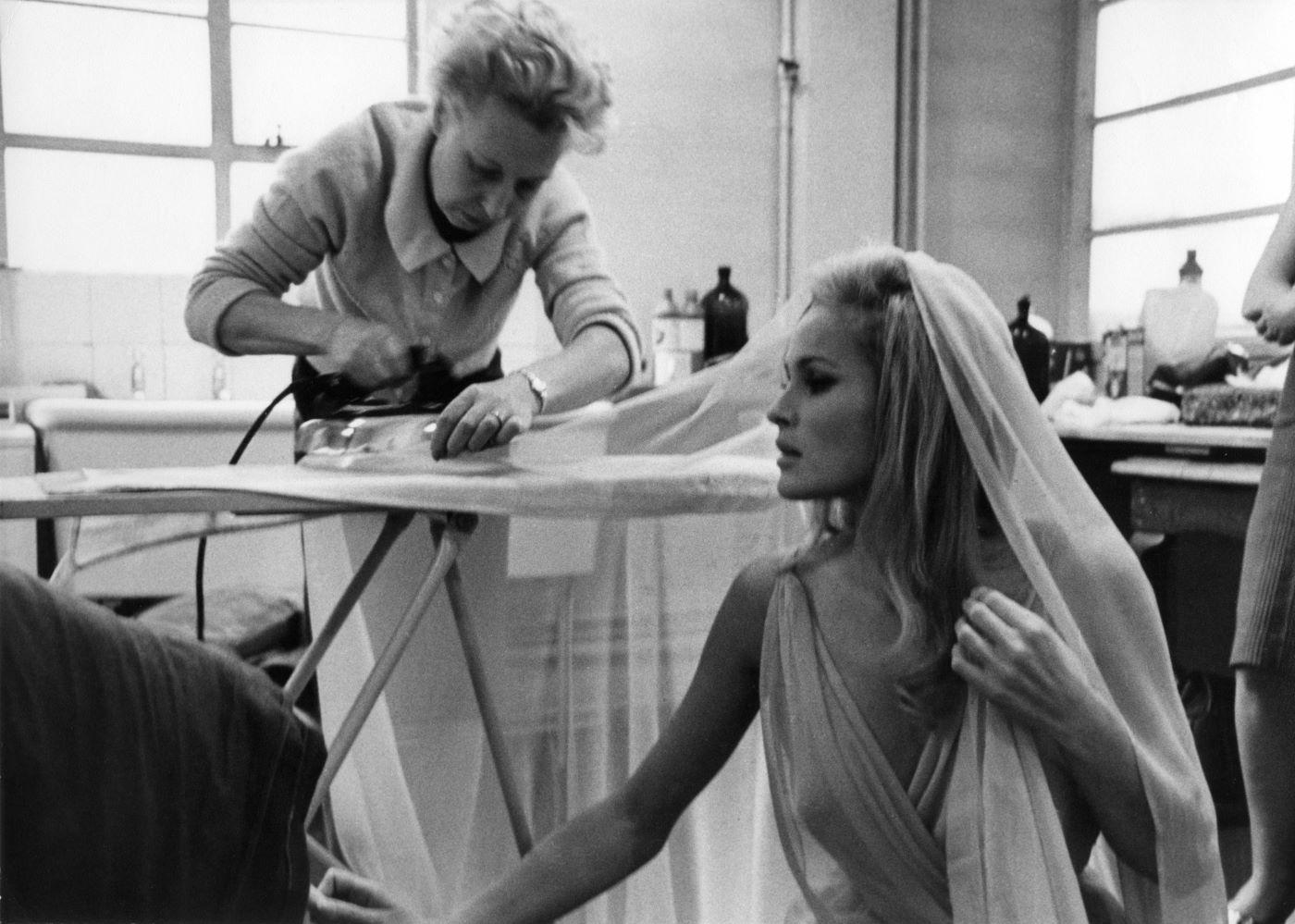 Wardrobe Mistress Jackie Cummins making sure that Ursula Andress is free of wrinkles for her starring role in She (1965)