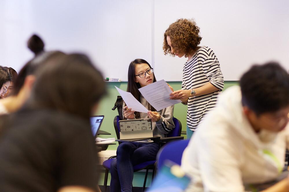 Teacher looking at work with students in class.
