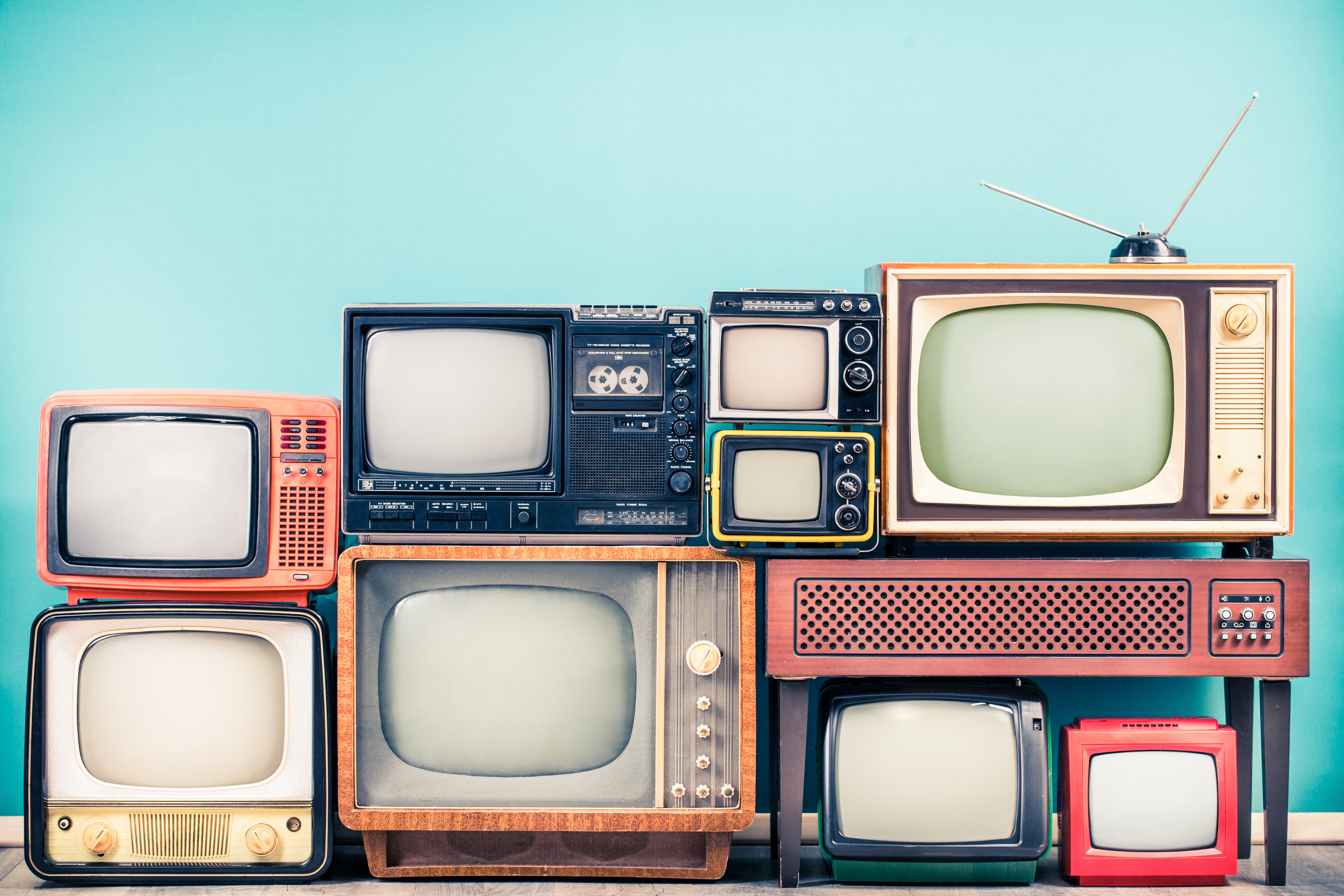A stack of old TVs against a blue background
