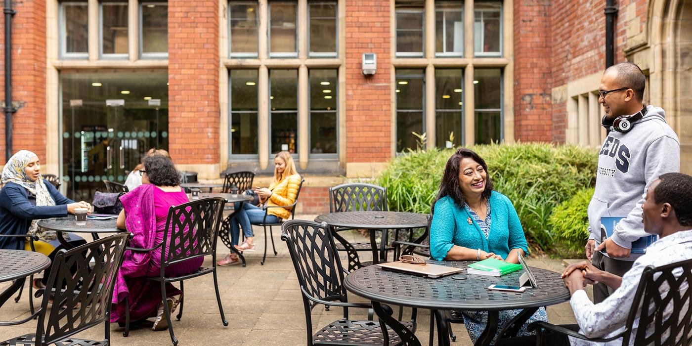 Postgraduate researchers sitting at tables outside Baines Wing