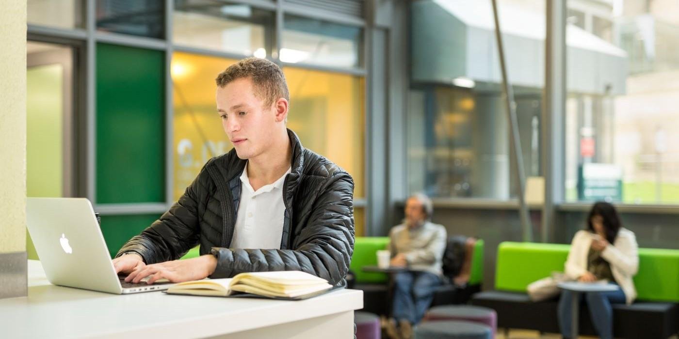 Student using laptop in open-plan study area