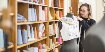 Student working with textiles on mannequin in the School of Design