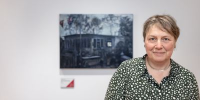 Dr Judith Tucker standing in front of her painting at Leeds Artist Show 2023