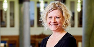 Headshot of Professor Karen Burland smiling stood on the balcony of the Brothernton Library, the background is out of focus.