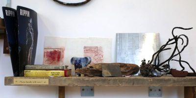 books, material tests, objects and sketches on a shelf made of reclaimed wood