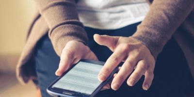 Woman's hands holding smartphone in lap