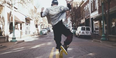 A man, seen from the back, dancing in the middle of the road.