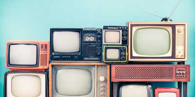 A stack of old TVs against a blue background