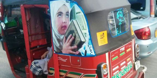 Motorized rickshaw with photo of a girl holding a holy book,