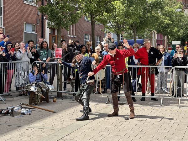 Two men re-enact a fight with medieval weaponry and armour