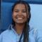 Portrait of Esta-Rose Nyeko-Lacek smiling against blue backdrop