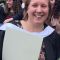 Picture shows a women with short fair hair smiling and wearing a graduation gown