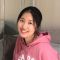 Image for Amber Zhang's student profile. Amber is smiling in front of a neutral coloured background and wears a pink hoodie with white text on the front, on which you can only see the top of the letters.
