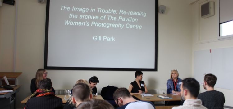 Panel of speakers with a powerpoint slide facing an audience
