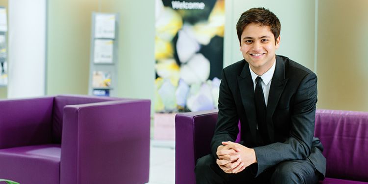 Student in suit sat on sofa.