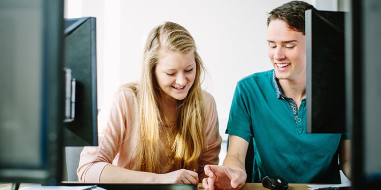 Two people at a desktop.